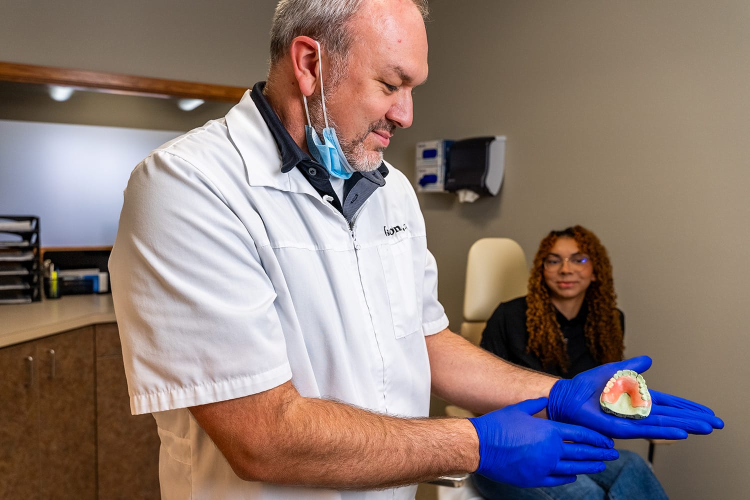 denturist showing denture to patient