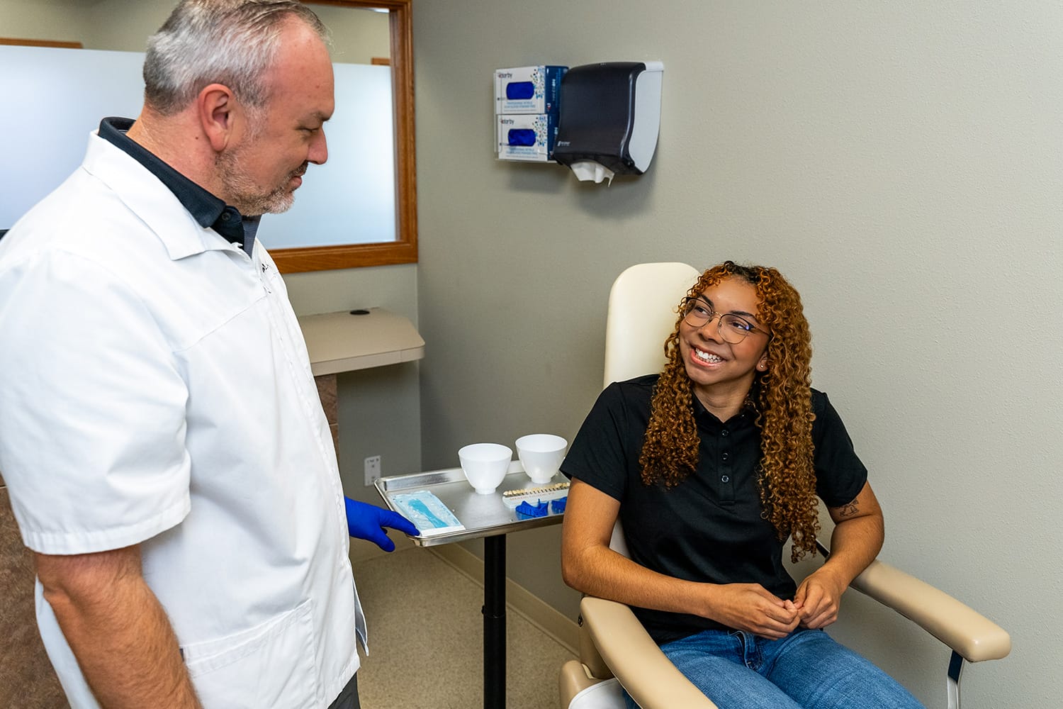 denturist with smiling patient in chair